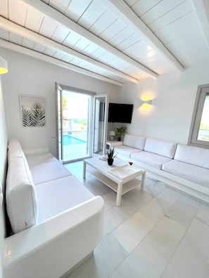 Ein modernes Wohnzimmer mit einem weißen Sofa, einem Couchtisch und einem an der Wand befestigten Fernseher.