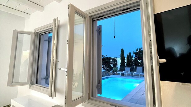 A room with a pool view, a TV, and a window with blinds.
