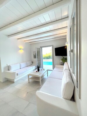 A modern living room with a white sofa, a coffee table, and a TV mounted on the wall.