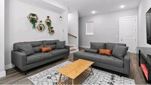 A modern living room with two grey sofas, a wooden coffee table, and hexagonal wall decorations.
