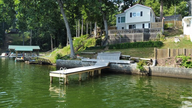 Una propiedad frente al lago con muelle, rampa cubierta para embarcaciones y una casa con terraza.