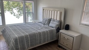 Un dormitorio con cama, mesita de noche y ventana con vista a árboles.
