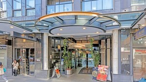 A modern building with a curved glass entrance, a sign for 'mantra Sydney Central', and a 'Fortune Abalone' sign.