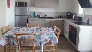 A compact kitchen with a dining table, chairs, a microwave, a sink, and a stove. - Apartment small building all on port and sea 5 min beach (Noirmoutier-en-l'Île)