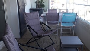 A balcony with two reclining chairs, a small table, and a potted plant. - Apartment small building all on port and sea 5 min beach (Noirmoutier-en-l'Île)