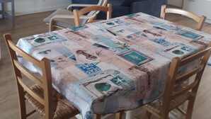 A dining area with a table covered in a patchwork tablecloth, surrounded by wooden chairs. - Apartment small building all on port and sea 5 min beach (Noirmoutier-en-l'Île)