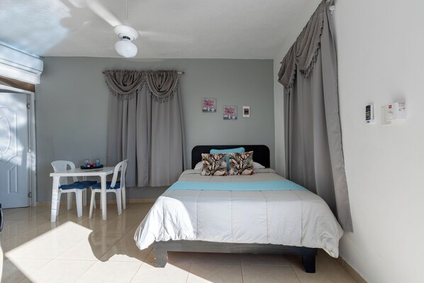 A bedroom with a bed, a desk, chairs, and curtains. - Stylish loft in the city/ Wi-fi / Jacuzzi (Samaná)