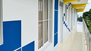 A corridor with tiled flooring, white walls with blue accents, and windows with metal bars. - Stylish loft in the city/ Wi-fi / Jacuzzi (Samaná)