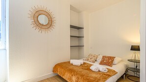 Un dormitorio con cama, un espejo en la pared, una mesita de noche y una lámpara.