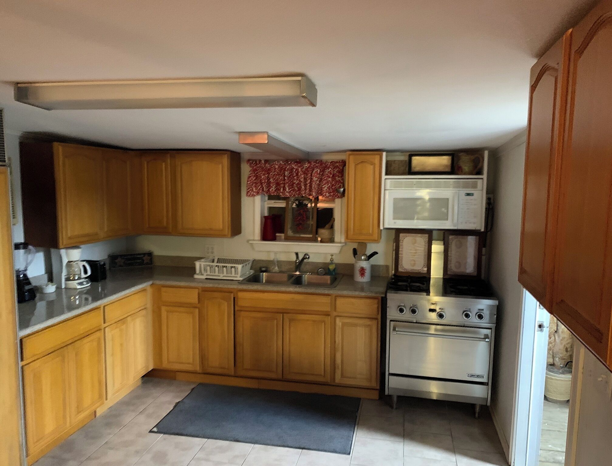 A compact kitchen with wooden cabinets, a microwave, a stove, and a sink.