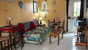 Une pièce comprenant un lit, un bureau, une chaise, un ventilateur de plafond et une fenêtre.