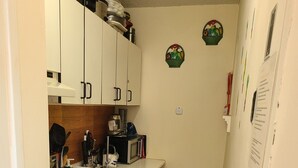 Une cuisine de taille réduite avec des meubles blancs, une cuisinière, un four à micro-ondes et une poubelle.