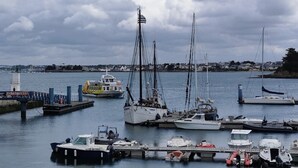A marina with various boats docked, a lifeboat, and a pier with a sign.