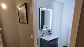 A modern bathroom with a vanity, mirror, and toilet.