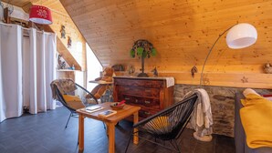 Une pièce chaleureuse avec un plafond en bois, une table à manger avec des chaises, un canapé et une lampe.