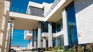 En moderne bygning med en glasfacade, flere etager og en markant trappe.