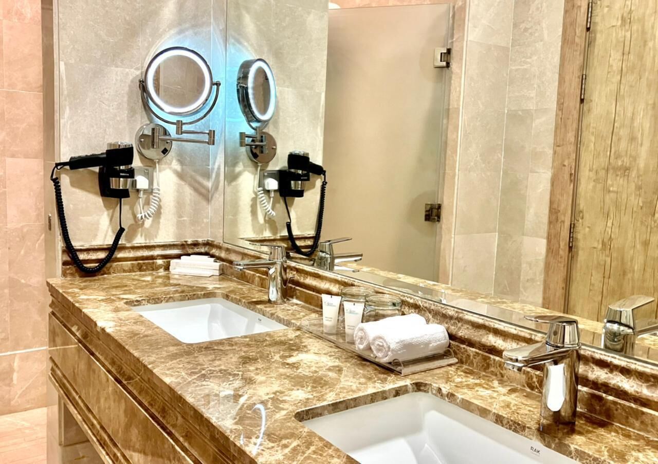A bathroom with two sinks, a large mirror, and a hairdryer.