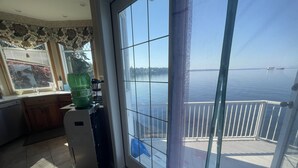 A kitchen with a large window overlooking a balcony with a view of the water.