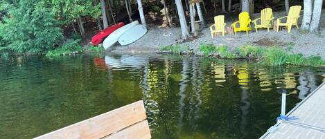 Une jetée en bois s’étendant sur une étendue d’eau, avec un banc et des chaises jaunes à proximité.