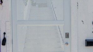 A white metal gate with a perforated design, a mailbox, and a small mailbox on the wall. - CENTRALLY-LOCATED CONDO (San Juan)