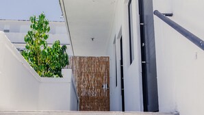 A modern building with a white exterior, a staircase leading to the entrance, and a bamboo fence. - CENTRALLY-LOCATED CONDO (San Juan)