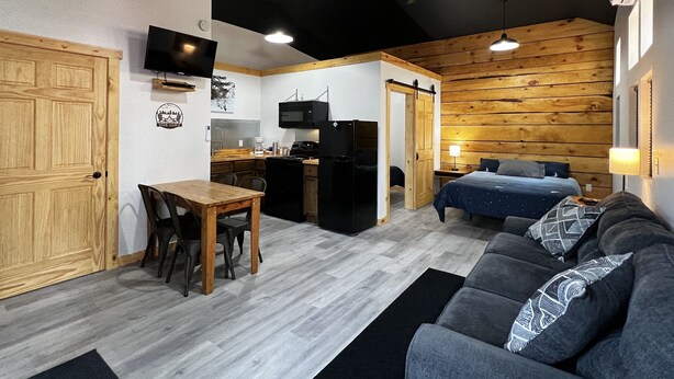 A compact living space with a kitchenette, a dining area, and a bedroom.