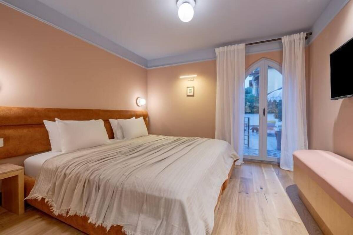 Une chambre à coucher avec un lit, une table de chevet et un téléviseur fixé au mur.