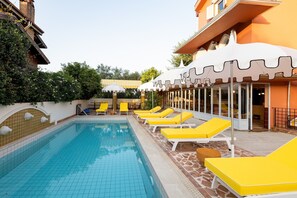 A swimming pool with yellow lounge chairs and a covered seating area. - Yonca Anjelika Otel (Fethiye)