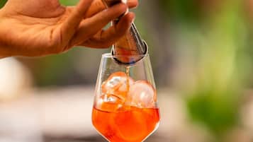 Eine Hand gießt einen Drink aus einem Shaker in ein mit Eis gefülltes Glas.