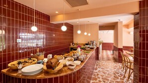 A buffet setup with a variety of food items, including bread, fruits, and salads, in a room with red tiled walls and a patterned floor. - Yonca Anjelika Otel (Fethiye)