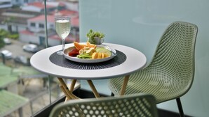 Una mesa de comedor con un plato de fruta, un vaso de agua, una planta pequeña y una silla.