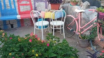 Un jardin sur le toit, avec une table et des chaises, un vélo rose et un banc orné de graffitis colorés.