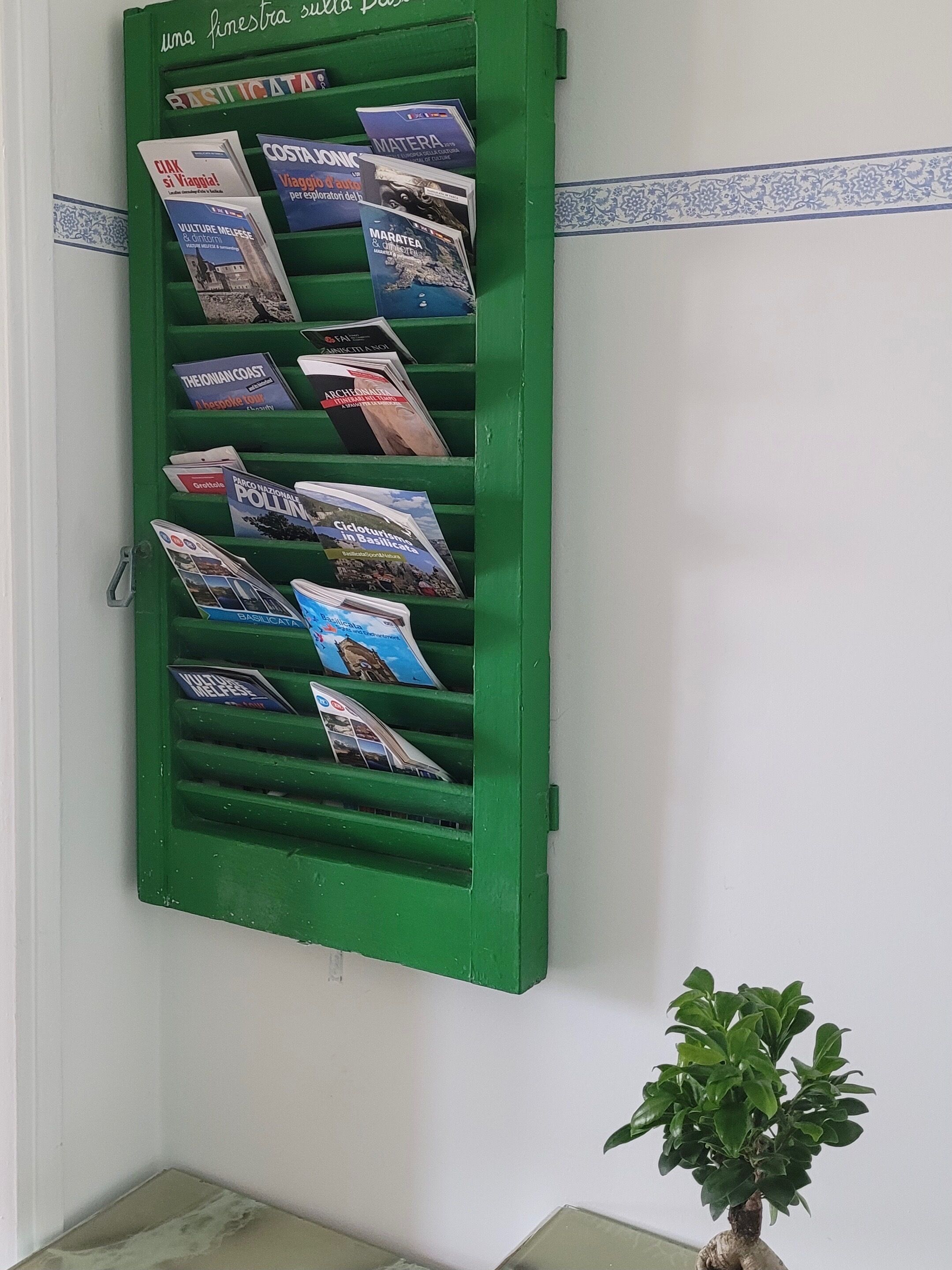 A green brochure rack with various travel guides and maps.