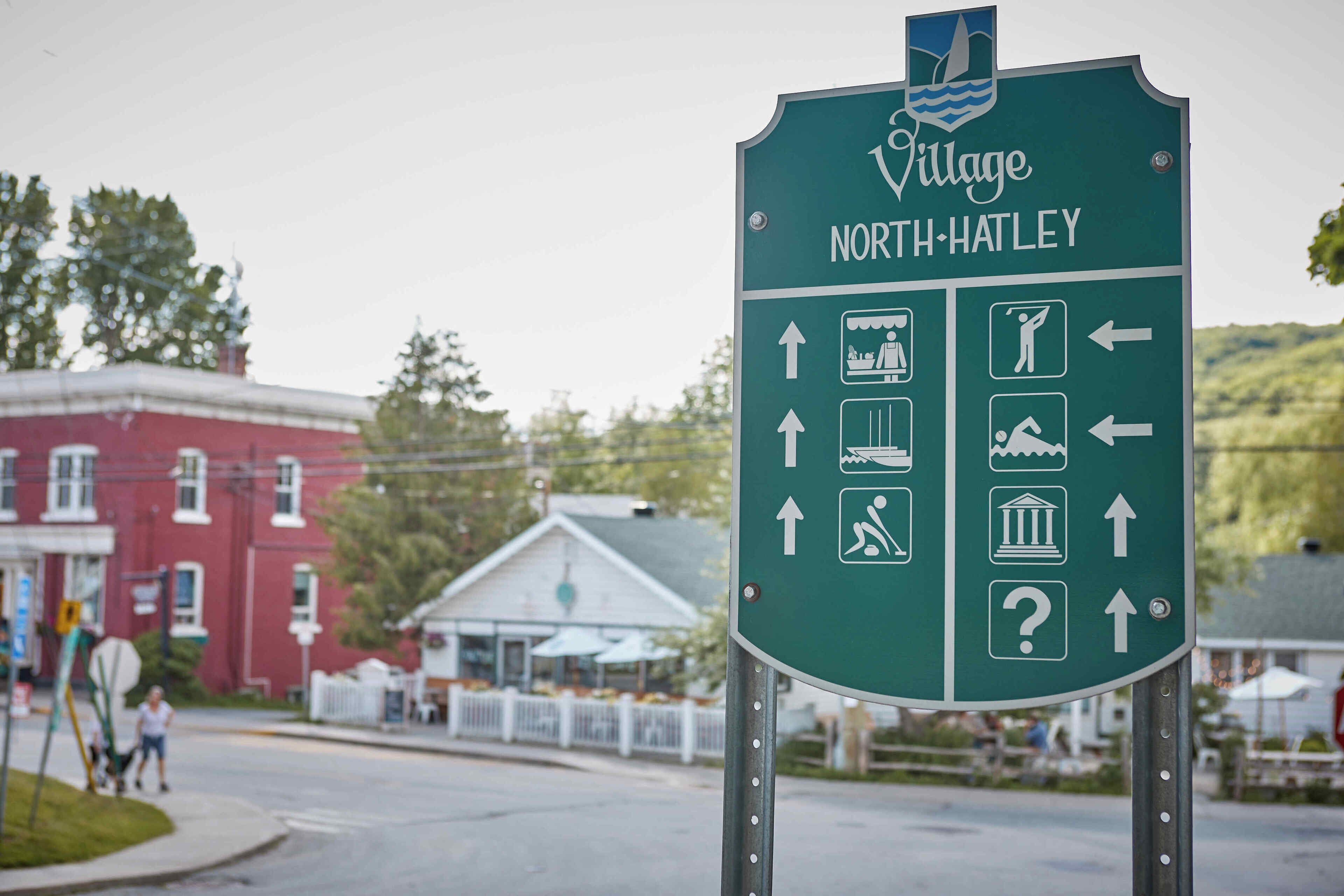 A directional sign for Village North Hatley with symbols indicating various amenities.