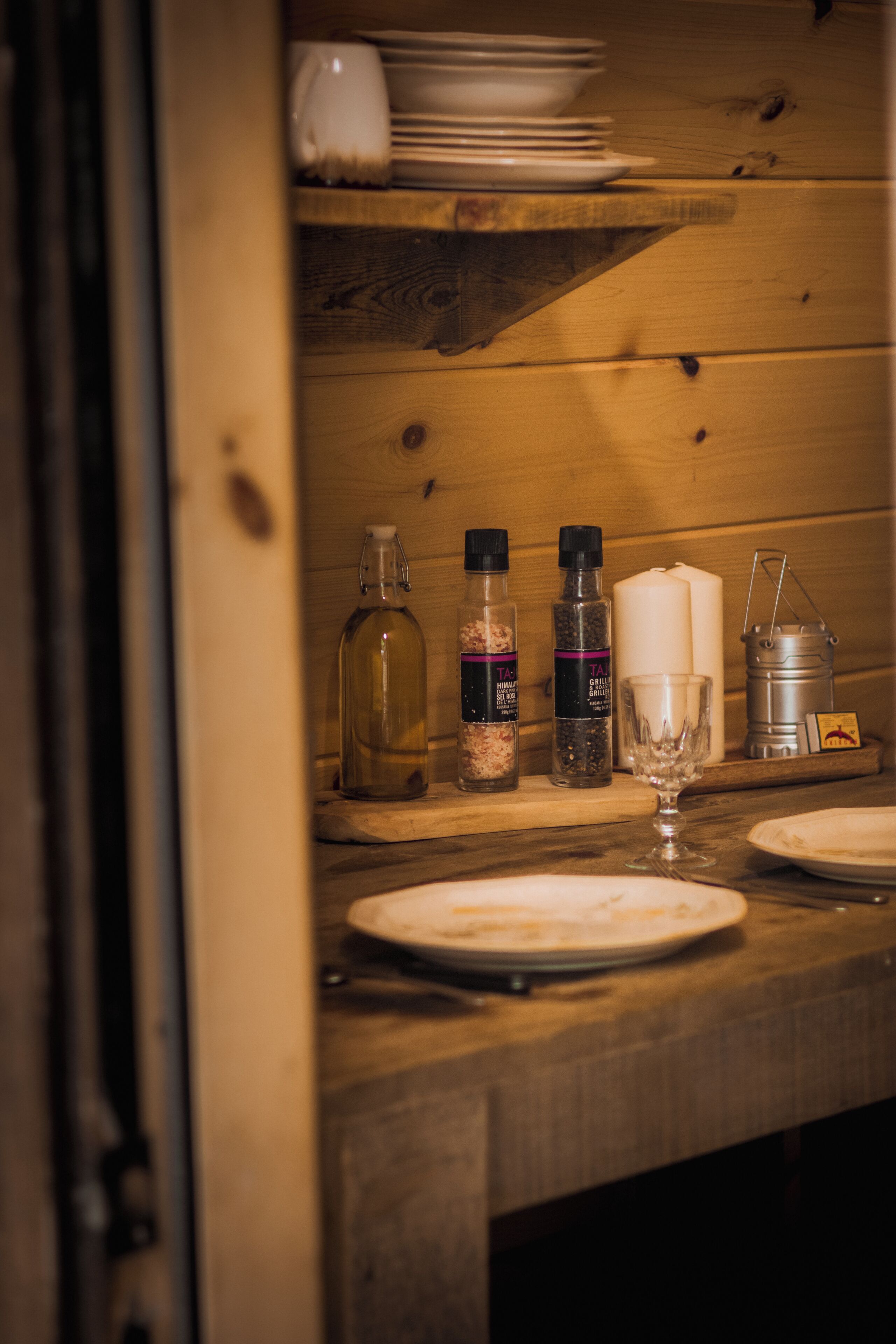 Een houten tafel met borden, een kaars en flesjes kruiden.