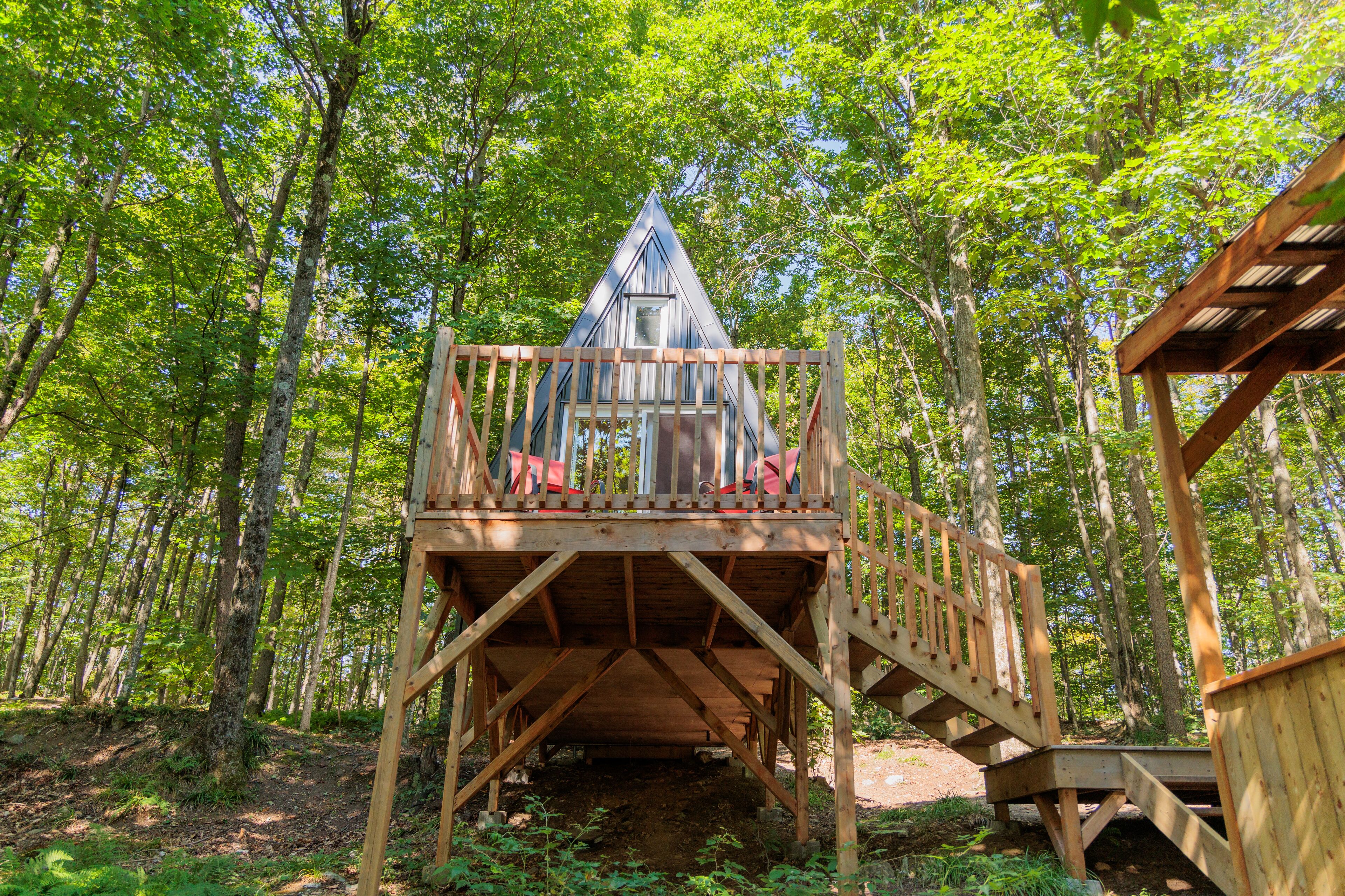 A wooden treehouse with a triangular roof and a wooden deck.