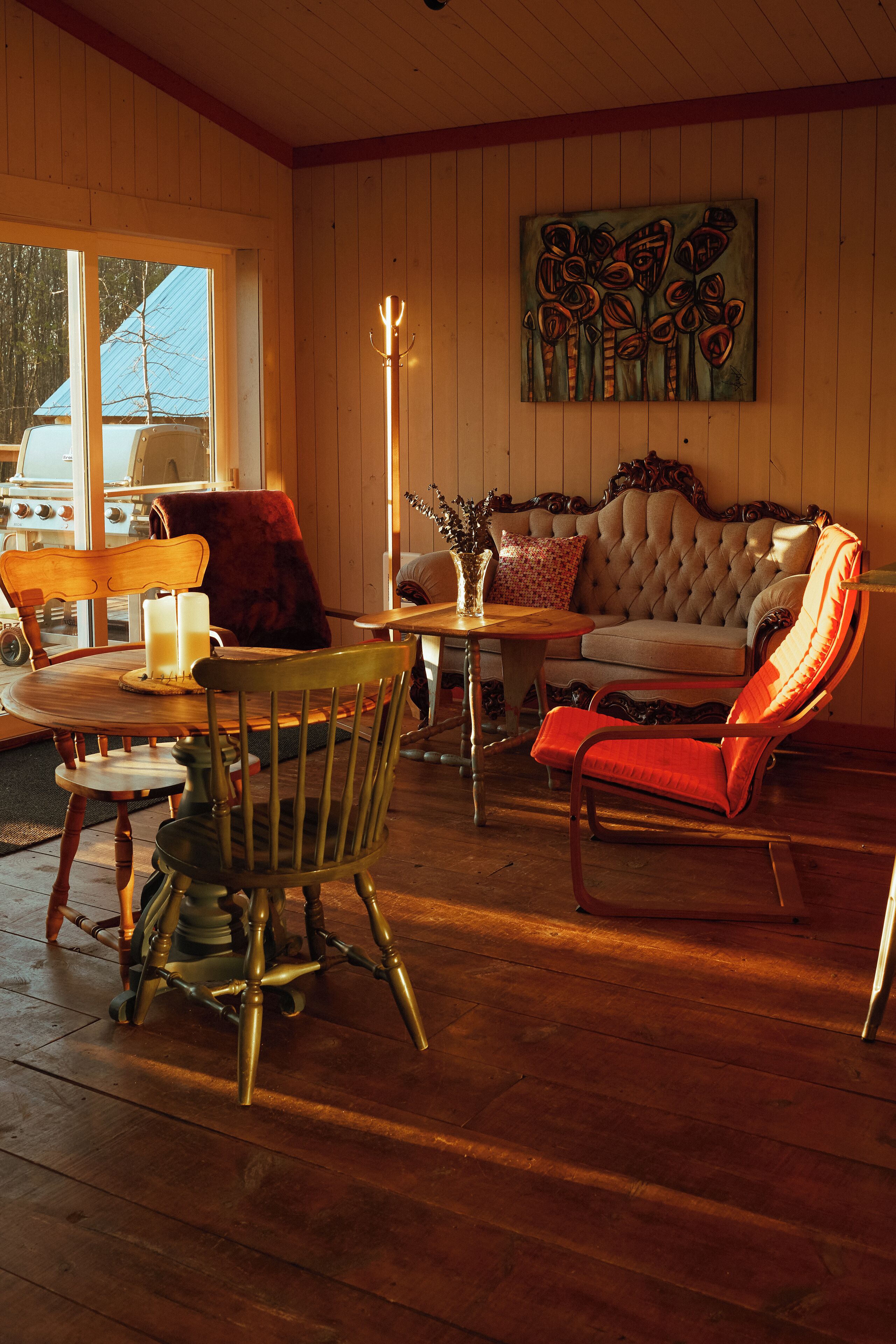 A cozy room with a wooden floor, a cushioned sofa, a wooden dining table, and a chair.