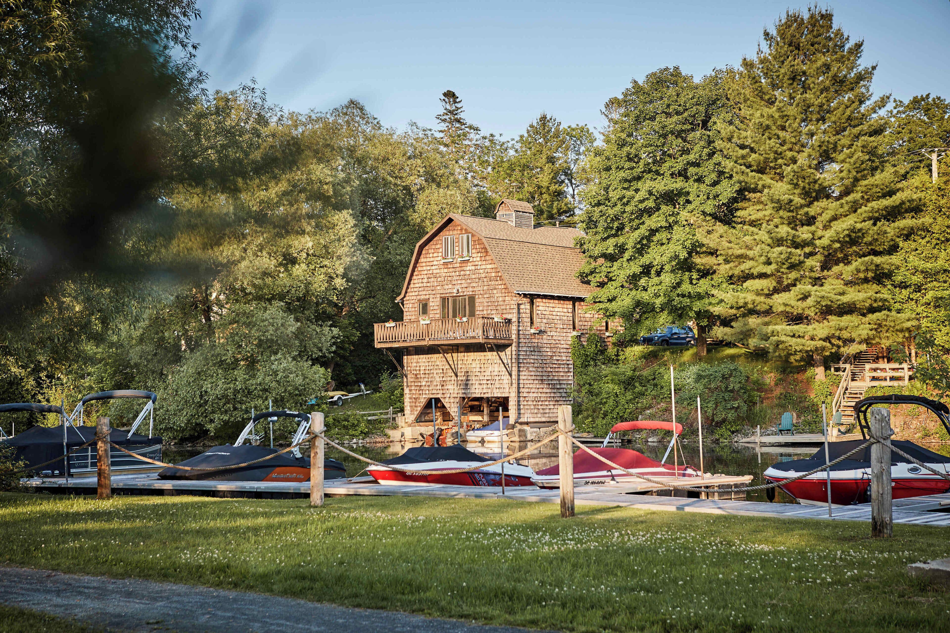 A stone building with a balcony, surrounded by boats and trees.