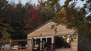 A wooden cabin with a deck and lounge chairs by a pool. - Station Chêne Rouge (Hatley)