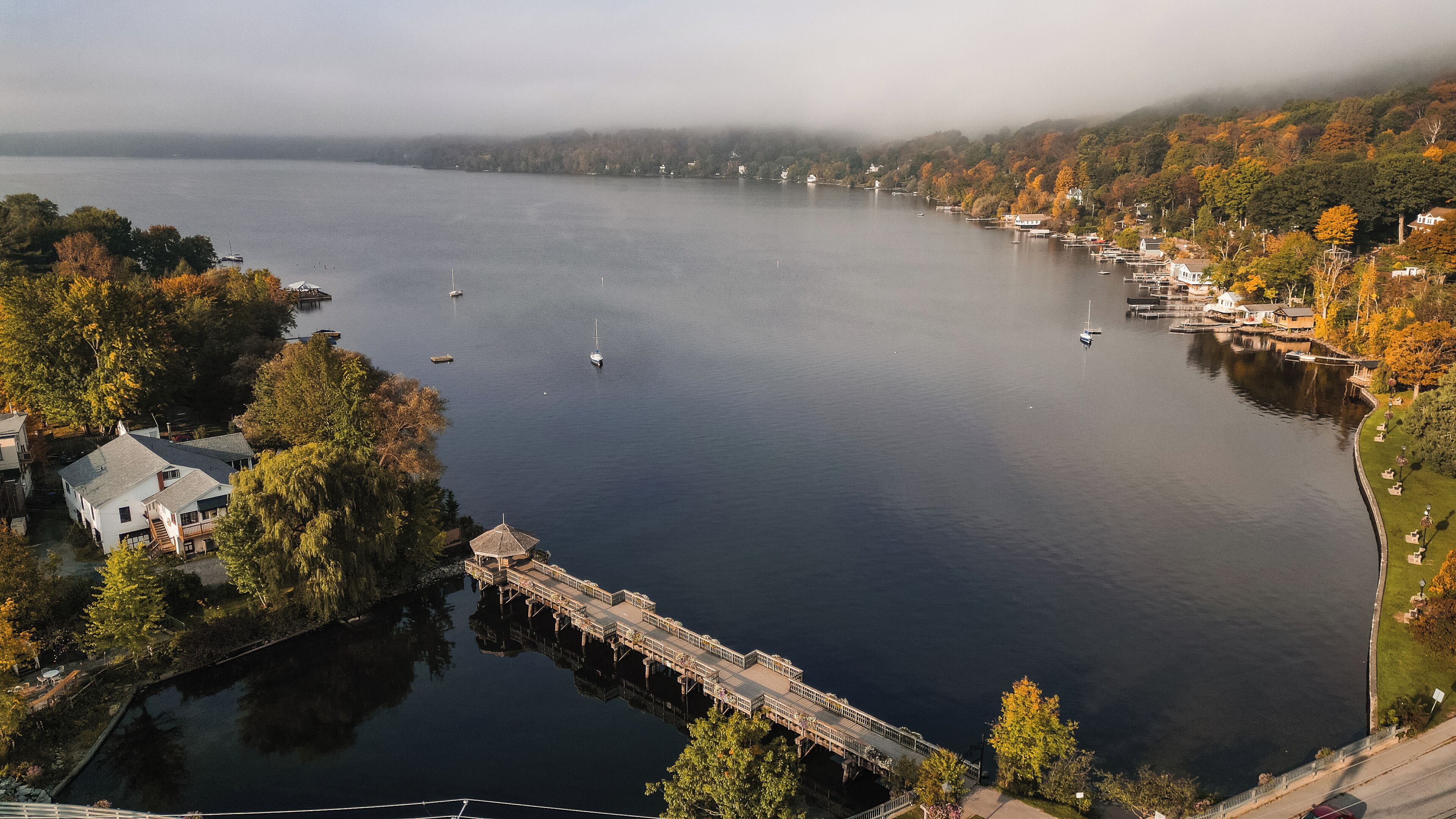 A lake with boats, a dock, and houses along the shore.