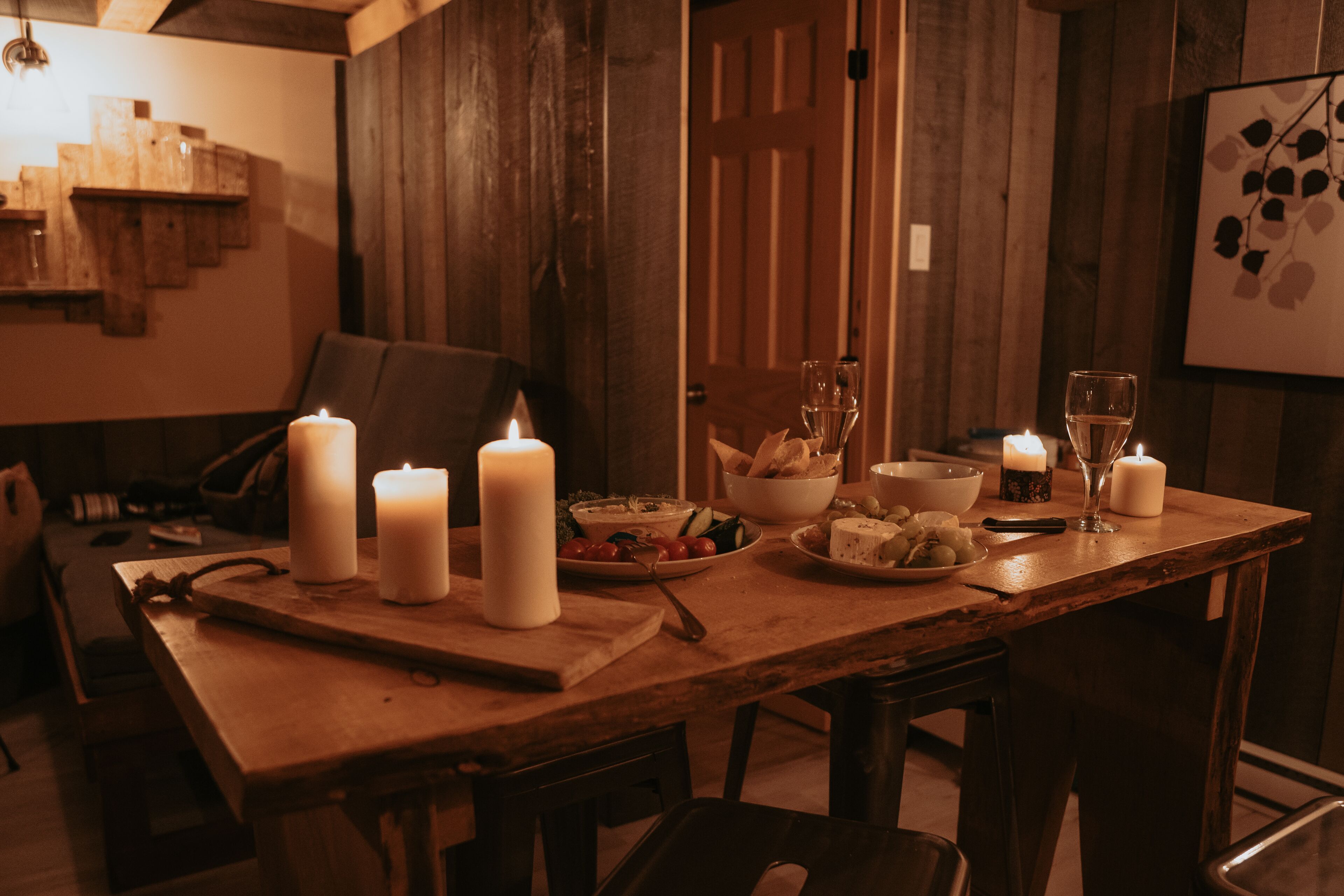 A wooden dining table set with candles, plates of food, and glasses.