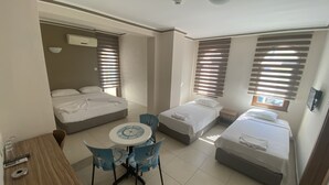 A hotel room with a bed, a smaller bed, a table with chairs, and a window with blinds. - Astoria Life Hotel (Marmaris)