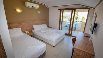 A hotel room with two beds, a desk, and a sliding glass door leading to a balcony.