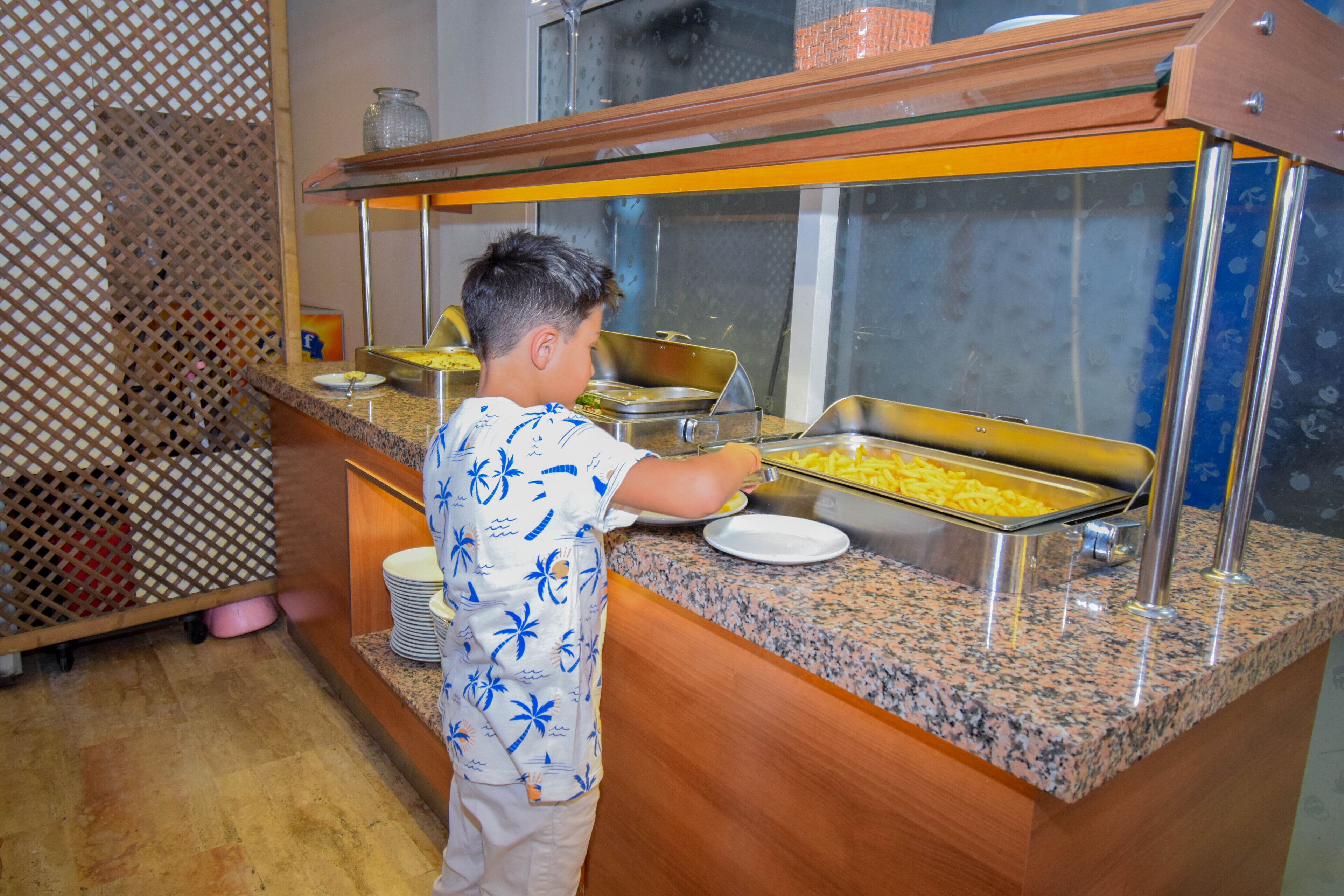 Un bufé con diversas opciones de comida y una persona atendiendo.