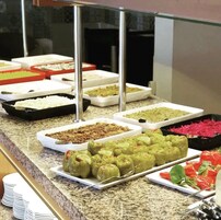 Buffet com diversos pratos, incluindo arroz, carne e legumes.
