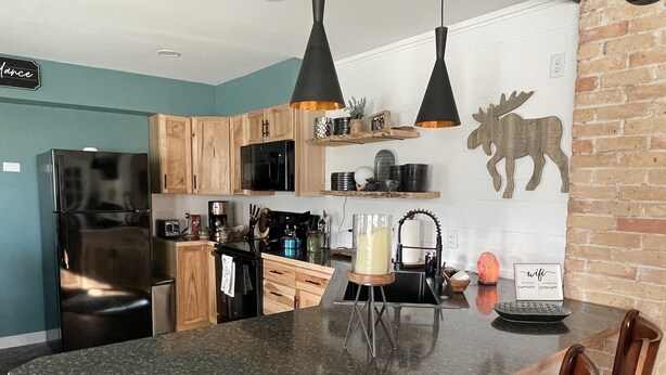 Una cocina moderna con una isla central, armarios de madera y un refrigerador negro.