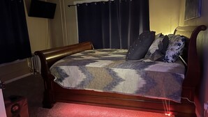 Un dormitorio con una cama de madera, una colcha estampada y una alfombra roja.