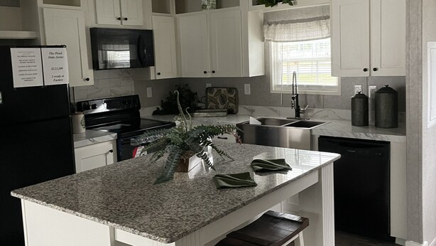 A modern kitchen with white cabinetry, granite countertops, and a central island with stools.