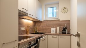Een moderne keuken met een ingebouwde oven, een vaatwasser en een raam boven de gootsteen.