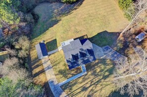 Luchtbeeld van een huis met een ruim terras, omringd door bomen en open velden.